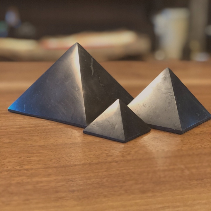 Su un tavolo, appoggiate tre piramidi di shungite di diverse dimensioni