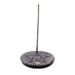 Supporto in ceramica rotondo con stella scolpita e bastoncino d’incenso sottile inserito al bordo.