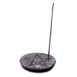 Supporto rotondo in ceramica con stella scolpita e bastoncino d’incenso sottile inserito al bordo.