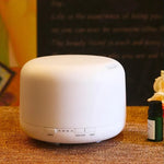 Diffusore bianco su tavolo con boccettina di olio essenziale