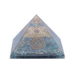 Piramide orgonite trasparente con cristallo di quarzo avvolto in spirale di rame e simbolo “fiore della vita” in metallo dorato incastonato frontalmente.