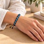 Bracciale Artigianale in Apatite Blu con Macramè - 8 mm indossato al polso in un ambiente naturale. Immagine generata con AI.