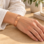 Bracciale magnetico in rame con fasi lunari incise, aperto e regolabile, indossato al polso.