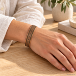 Bracciale magnetico in rame Fiore della Vita con fondo scuro e bordi decorati, indossato al polso.