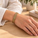 Bracciale magnetico in rame Fiore della Vita con motivo dorato su fondo nero, regolabile e indossato al polso.