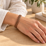 Bracciale magnetico in rame intrecciato a maglie, aperto e regolabile, indossato al polso.