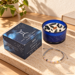 Candela Gemelli dello Zodiaco con confezione e braccialetto, ambientata su una consolle in legno.