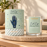 Candela profumata Celestial Magic Palo Santo e Patchouli, con confezione illustrata, ambientata su una consolle in legno.