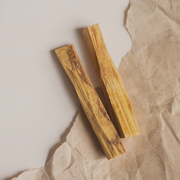 Due bastoncini di palo santo appoggiati sul tavolo, sopra della carta