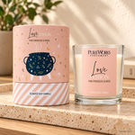 Candela profumata Celestial Magic Pink Prosecco e Rosa, con confezione illustrata, ambientata su una consolle in legno.